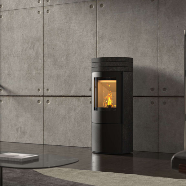 Ein Vaio IQ Kaminofen steht in einem Wohnzimmer vor einer Betonwand und ist in ein Bücherregal rechts und ein großes Fenster links eingeschlossen.