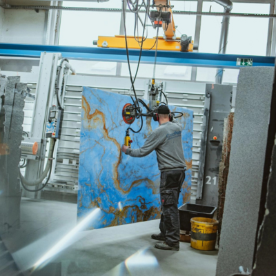 Arbeiter bewegt ein großes Steinbild mit einer Hebevorrichtung in einer Werkhalle.