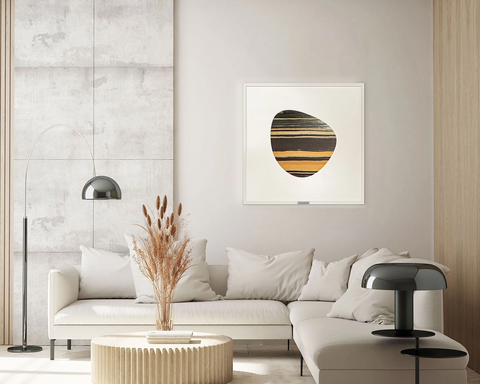 Ein Steinbild mit Passepartout hängt in einem hellen Wohnzimmer über einer großen Couch mit Beistelltisch und Deko.