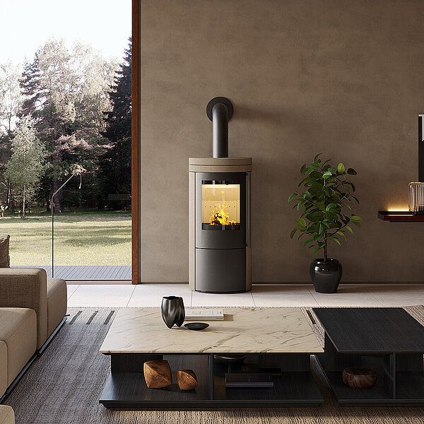 Kaminofen steht in einem modernen, in Brauntönen eingerichteten Wohnzimmer, mit Couch und Tisch, neben einem Fenster.