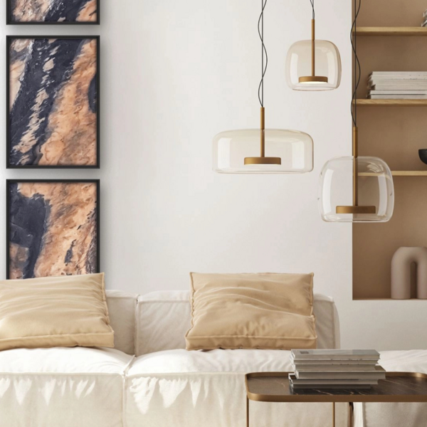 Drei Steinbilder hängen übereinander neben einem Regal an einer Wand, vor der ein Sofa mit Tisch steht.