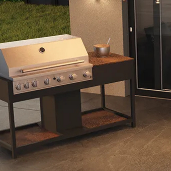 Der Gasgrill CB CeraKitchen steht auf einer Terrasse vor einer Hauswand und Garten.