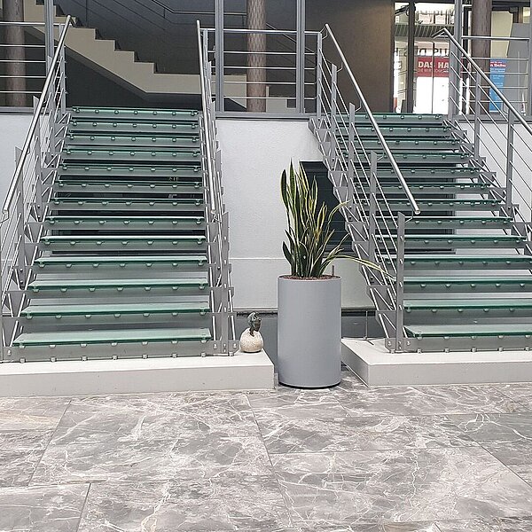 Eingangsbereich mit mehreren Pflanzen und zwei Treppen, die eine Etage höher führen.