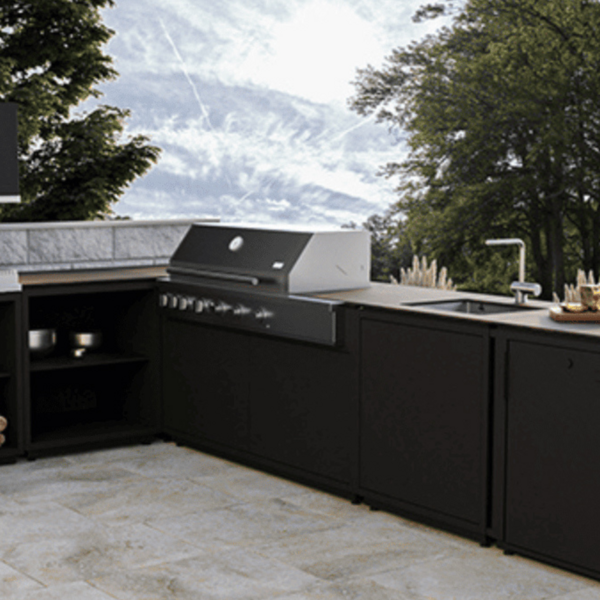 Eine Außenküche steht auf einer Terrasse in einem Garten.