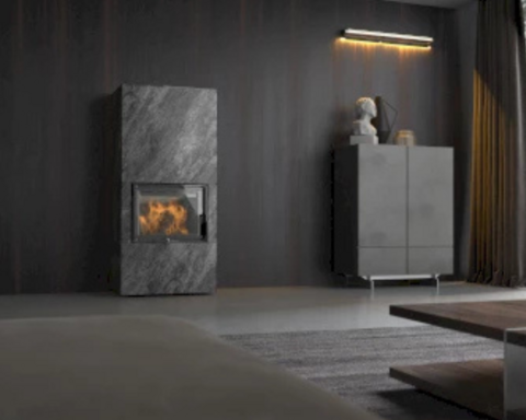 Der neocube Frame Kaminofen steht vor einer grauen Wand in einem dunkel eingerichteten Wohnzimmer.