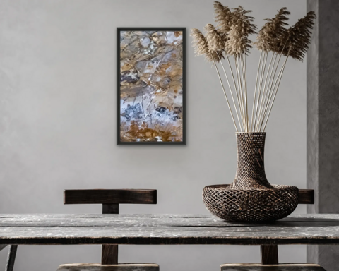 Im Hintergrund hängt ein buntes, vollflächiges Steinbild an einer hellgrauen Wand, vor der ein Tisch mit zwei Stühlen und eine Vase stehen.