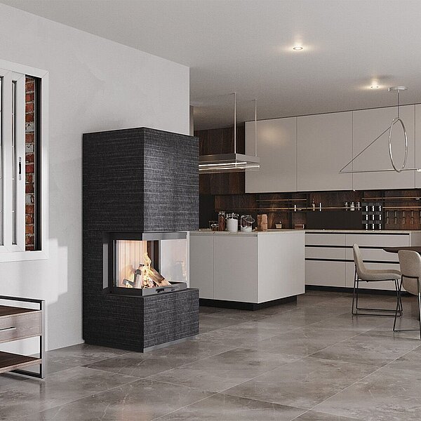 Ein schwarzer Kaminofen steht in einer offenen Küche mit Essbereich.