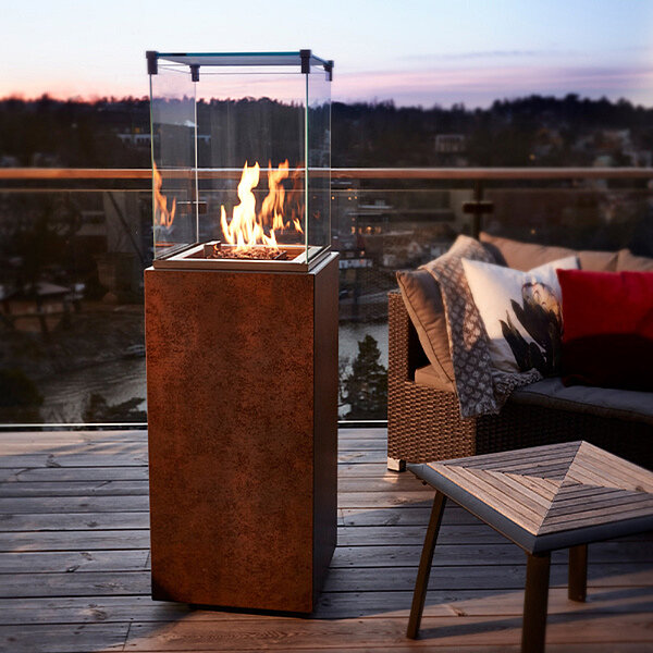 Ein Outdoor-Kamin steht auf einem Balkon neben einem Sessel.