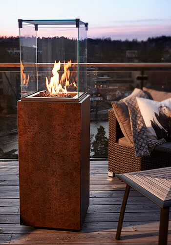 Ein Outdoor-Kamin steht auf einem Balkon neben einem Sessel.