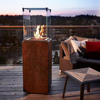 Ein Outdoor-Kamin steht auf einem Balkon neben einem Sessel.
