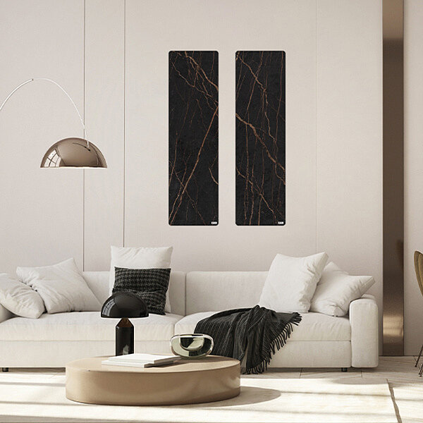 Hell und modern eingerichtetes Wohnzimmer mit Sofa über dem zwei schwarze Infrarotheizungen hängen.